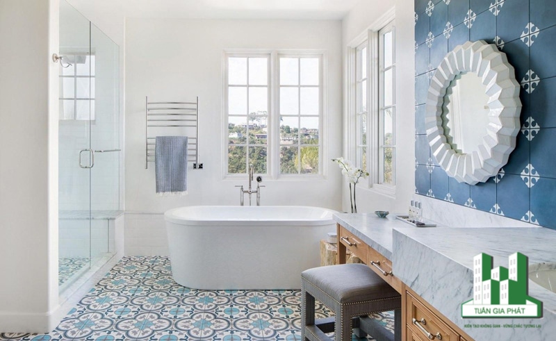 Những viên gạch có màu xanh ngọc tạo điểm nhấn cho sàn nhà, giúp không gian. nổi bật. Bức tường phía sau bồn rửa lát gạch màu xanh dương với chi tiết trang trí màu trắng kết hợp với chiếc gương hình tròn màu trắng.