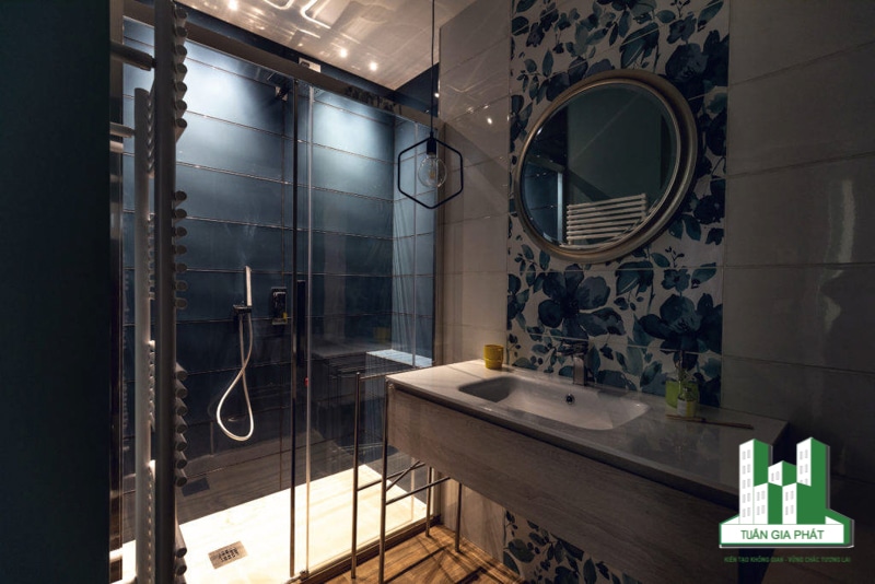 Phòng tắm hiện đại thêm sức hút với một viên gạch hoa màu xanh lam ngoại cỡ trên bức tường phía trên bồn rửa. Góc tắm vòi sen ốp gạch màu xanh thể hiện dụng ý sử dụng màu sắc trong thiết kế.